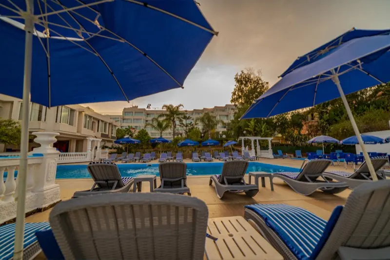 Piscine de l'Hôtel Raïs à la tombée du jour, avec la façade illuminée en fond