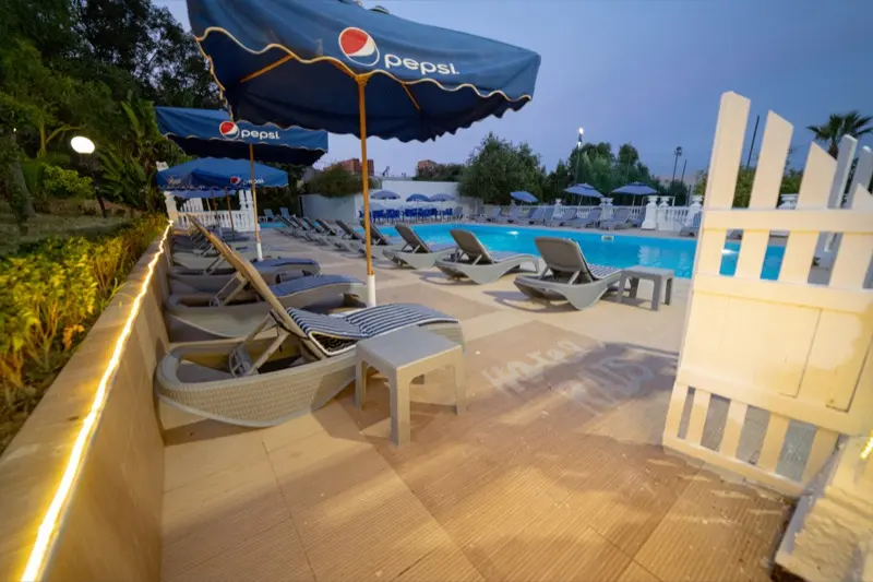 Transats et parasols au bord de la piscine le soir