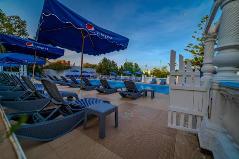 Espace piscine de l'Hôtel Raïs avec portail blanc et jardins
