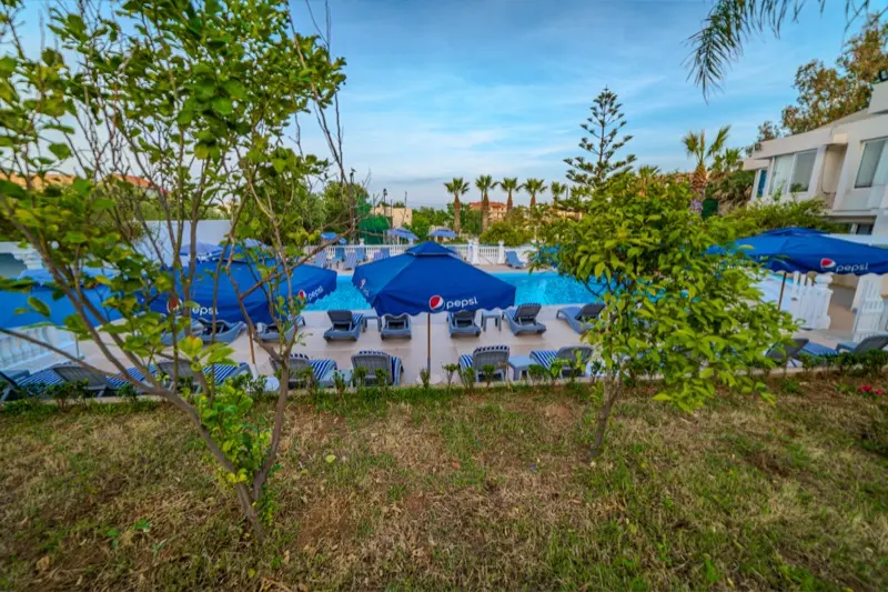Piscine de l'Hôtel Raïs aperçue à travers les frondaisons du jardin
