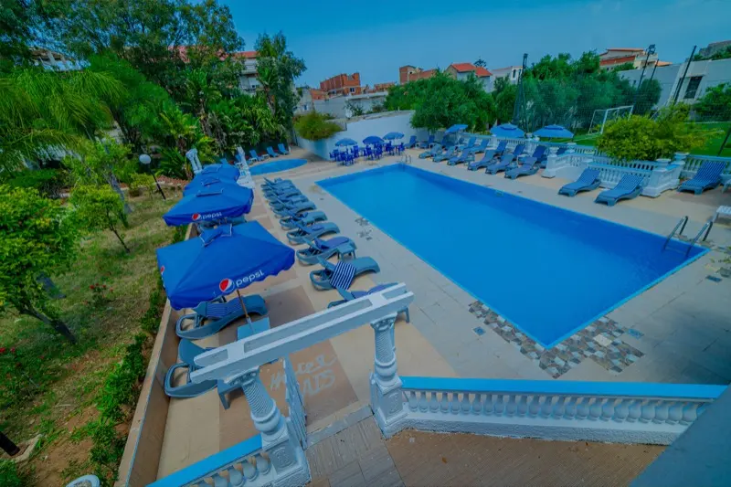 Vue d'ensemble de la piscine, transats et parasols de l'Hôtel Raïs